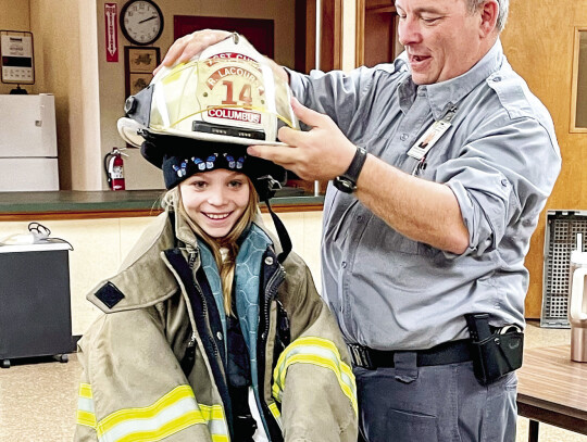 Girl Friends member getting suited up by Volunteer Firefighter Richard LeCourse.