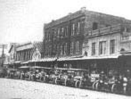 Downtown Eagle Lake citizens with cars facing out assembled to meet visitors to the town and prospective land buyers as a welcome event