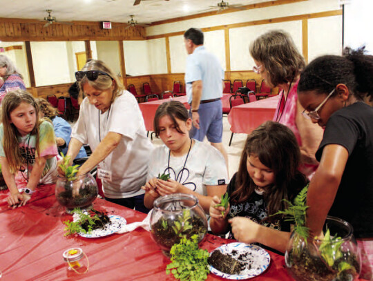 Volunteers and Kids Kamp participants putting together a terrarium. Citizen | Shayla Kuykendall