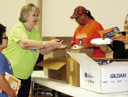 Astros Foundation volunteer John Morales, wife Jennifer Morales and Librarian Vicki Powers giving out Astros t-shirts and rally towels.