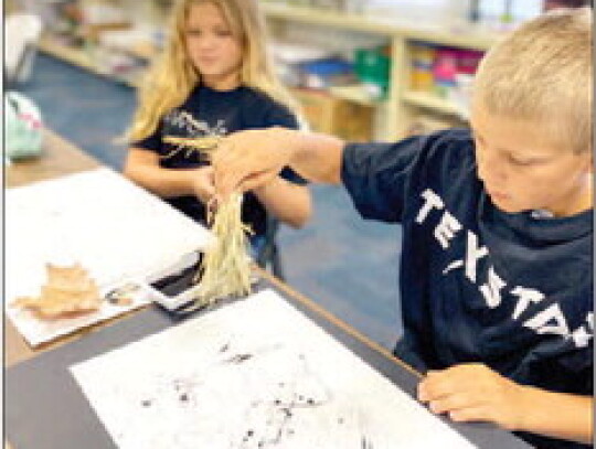 Sixth graders Macie Davis (left) and Justin Ohnheiser use leaves and grass for mark making and painting lines in art under the direction of their art teacher Brittney Herzek (not pictured) at St. Michael Catholic School in Weimar.