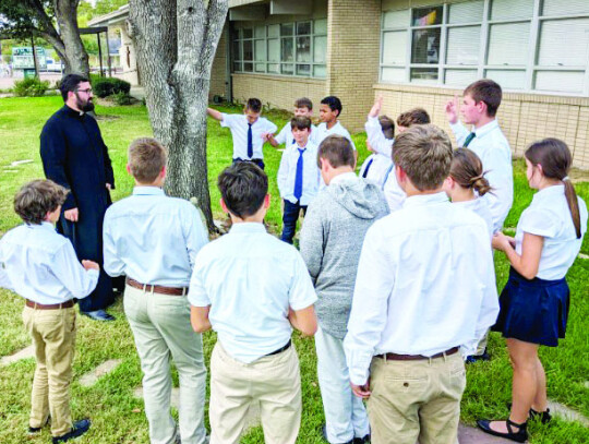 Above: Fr. Chase Goodman and St. Francis of Assisi portrayed by eighth grader Cullen Marek bless the animals of St. Michael students. Left: Chase Goodman, along with teachers Cara Janecka and Julia Hollek (not pictured), continued the Brothers and Sisters