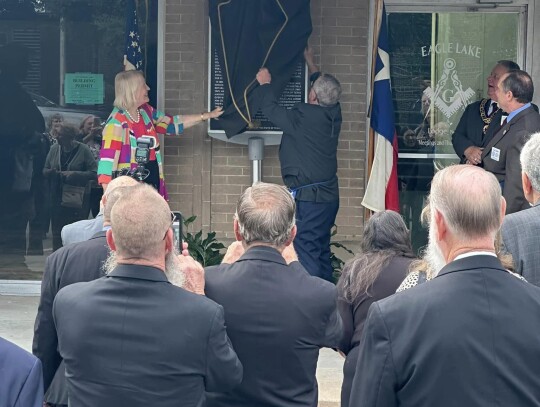 Dr. Sandra Thomas (left) helps Mason Charles Abel reveal the marker for the dedication as several Masons look on. Courtesy photo