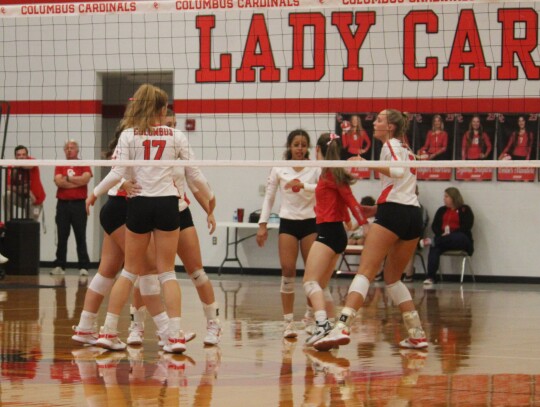 Lady Cardinals celebrate after Taylor Morrow earns the team a point with a kill. Photo by Evan Hale 