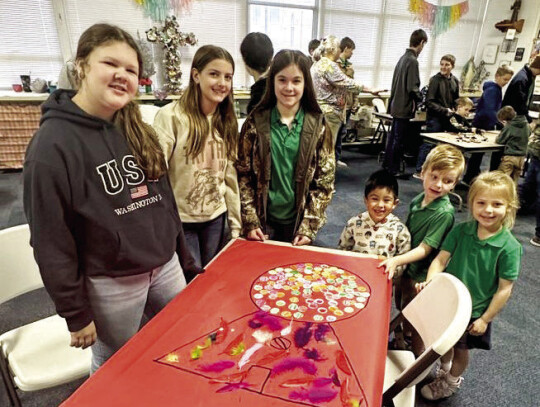 The Junior High students joined Kindergarten for 100th Day activities. Pictured here from left are seventh graders Emily Weid and Sarah Jane Berger, eighth grader Ella Herzik and Kindergartners Dylan Ambriz, Jacob Prichard-Jones and Kennedy Vanicek putting 100 gumballs in their giant gumba...