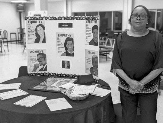 Debra Cummings stands next a table set up with programs, quotes and art.