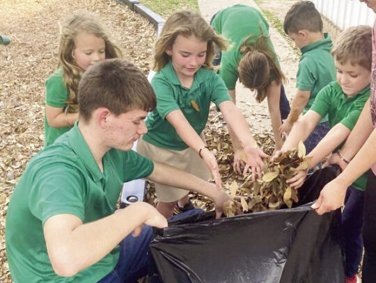 (Far left) Grant Janecka, Jesse Janecka and Lane Anders move a very heavy plant pot. (Left) Students in 8th and 5th grades also helped Pre-K 3, Pre-K 4 and Kindergartners clean and restore the small playground. Pictured from left are Collin Brown, Charlot